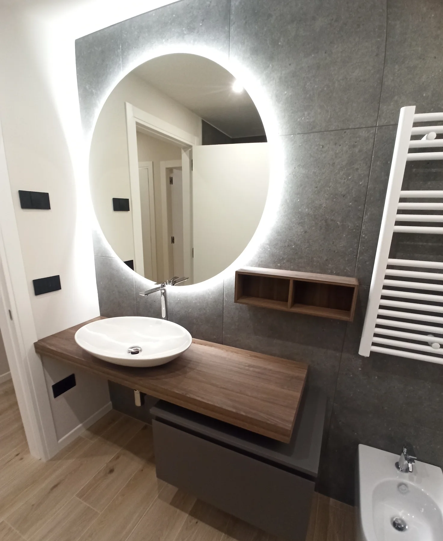 Lavabo d’appoggio su piano in legno con specchio retroilluminato